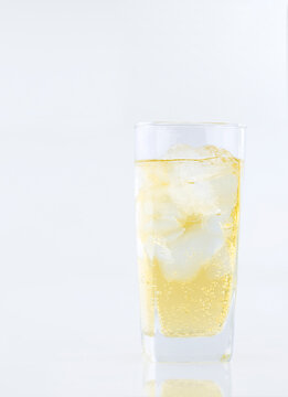 Alcohol with ice in glass on white table in vertical frame