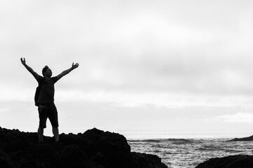 Man's silhouette standing on a cliff at the sea