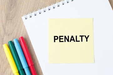 Penalty inscription on a yellow card lying on a notebook, office desk.