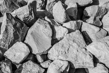 large natural stones piled up in the bright sun in black and white