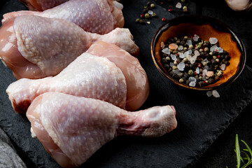  Raw chicken legs with spices on a black background close up