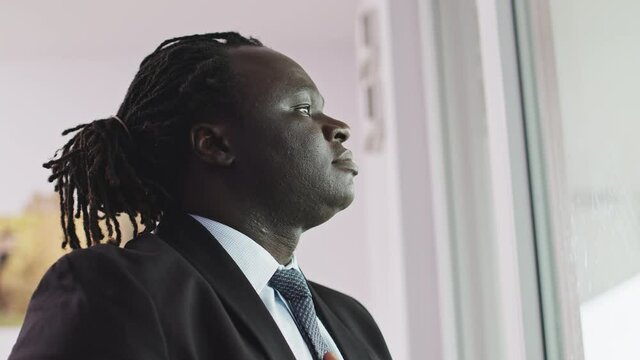 Profile of Young Black African Male in an Elegant Suit Fixing His Tie by Window. Wedding or Business Concept, Slow Motion