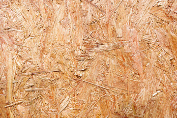 OSB are made of brown wood chips, ground into a wooden background. Top view of OSB wood veneer, dense, seamless surfaces.