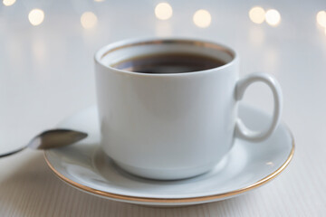 White cup of hot coffee on a light background.
