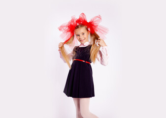 schoolgirl with bright tulle bows on her head in school clothes on a white background