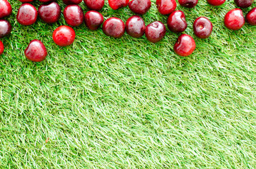 red fresh cherries on green grass, close view