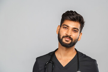 young indian male doctor or surgeon with stethoscope on gray background