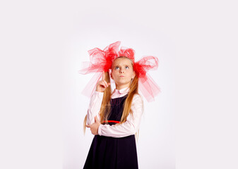 schoolgirl with bright tulle bows on her head in school clothes on a white background