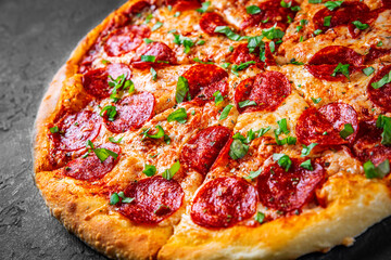 Pepperoni Pizza with Mozzarella cheese, salami, Tomato sauce, pepper, Spices. Italian pizza on Dark grey black slate background