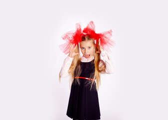 schoolgirl with bright tulle bows on her head in school clothes on a white background