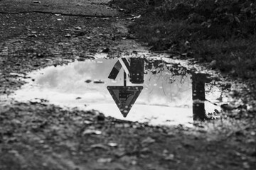 Traffic sign for ungated level crossing reflects in rain puddle