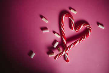 two lollipops in heart shape on pink background. Gifts for the New year and Christmas. top view