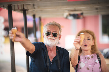 Senior couple happy and smiling with icecream at the amusement park. Turn back to the teenager time...