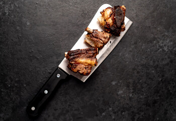 grilled beef ribs on a meat knife on a stone background