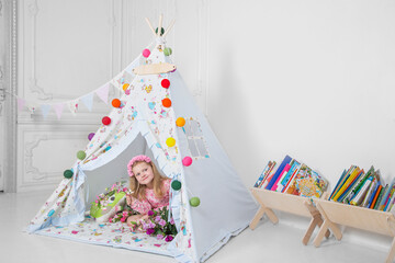 a little girl playing in a teepee