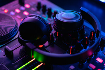 Obraz na płótnie Canvas Mesa controladora de sonido con auriculares de DJ encendida con colores morados y azules