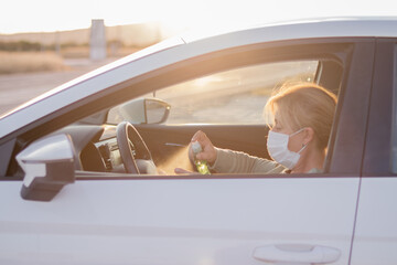 Fototapeta na wymiar Mujer con mascarilla en su vehículo desinfectándose las manos