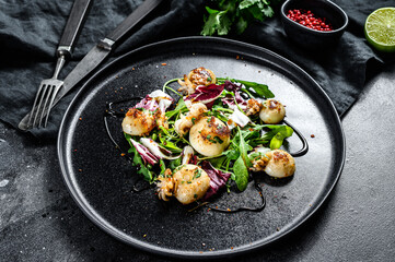 Thai salad with grilled squid and arugula. Black background. Top view