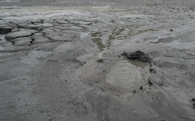 Mud liquid flowing from mud volcano, at Paclele Mari mud volcanoes in Buzau, Romania. Small volcano-shaped structures caused by the eruption of mud and natural gases.