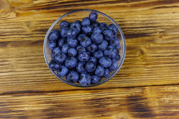 Fresh blueberry in glass bowl on a wooden table. Top view