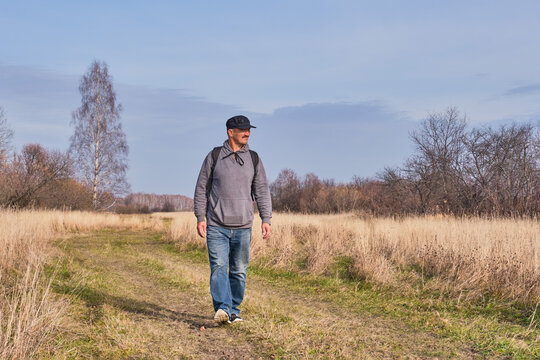 Active man in casual with backpack is walking in a meadow late autumn. Siberia, Russia.