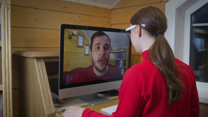 Back view of female employee speak talk on video call with colleague on online briefing, woman worker have webcam conference call with coworker on computer at home. Negotiations with partners