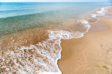 Waves with sea foam on a sandy beach