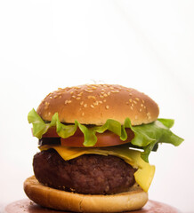 Big juicy burger with beef cutlet, fresh vegetables and melted cheese. Fast food, high-calorie food.