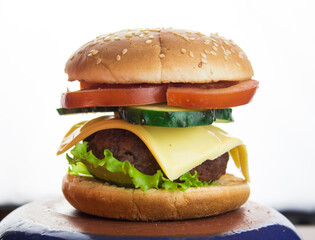 Big juicy burger with beef cutlet, fresh vegetables and melted cheese.