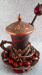 Rosehip tea in traditional Turkish copper tea set and spoons on an silver background.