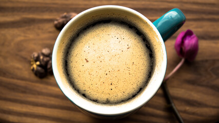 A cup of aromatic coffee stands on a wooden table.