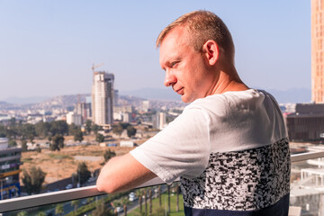 Man in the balcony at morning and watching urban view