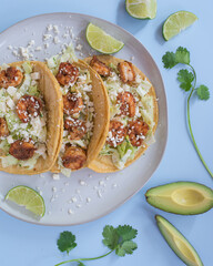 Shrimp tacos with avocado and blue background