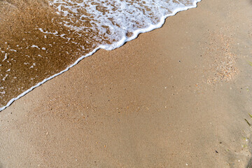 Waves with sea foam on a sandy beach