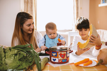 Young mother and children preparing meal with healthy food