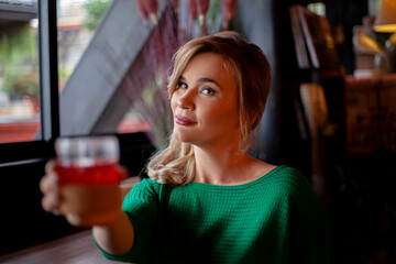 Young pretty woman eating tasty pumpkin puree soup  and drink tea  in urban cafe on New Year's Eve holidays