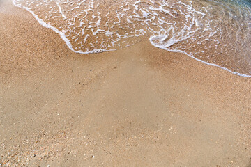 Waves with sea foam on a sandy beach