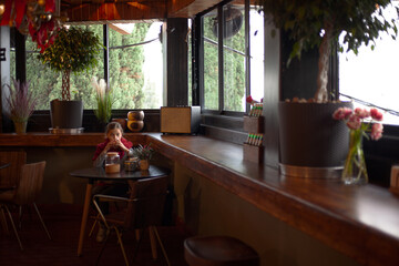 Young pretty pteteen girl  looks at the windskreen with sweets of eating something tasty in cafe on New Year's Eve holidays