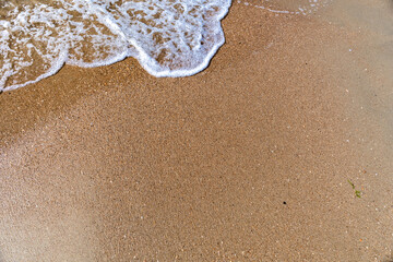 Waves with sea foam on a sandy beach