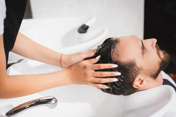 Obraz na płótnie Canvas hairdresser washing hair of client in barbershop