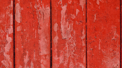 old wooden boards with red peeling paint with cracks. rough surface texture.