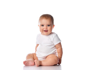 Little baby girl in white bodysuit sitting on the floor isolated on white.
