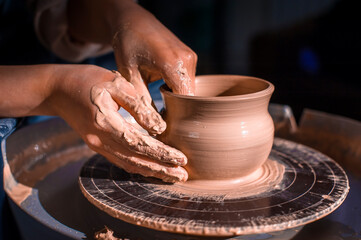 Women hands. Potter at work. Creating dishes. Potter's wheel. Dirty hands in the clay and the potter's wheel with the product. Creation. Working potter.