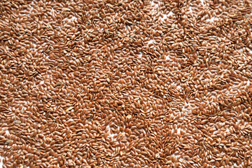 Irregular uneveb background of raw dry brown flax seeds