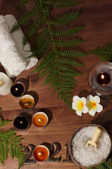 Golden numbers 2021 of a burning candle and a set for spa treatments with white sea salt on a wooden table