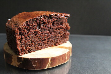 chocolate brownie pie on a wooden backing stand in a black place with copy space for text