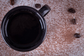 Black iron mug with coffee or black tea on the table with coffee grain and chocolate powder
