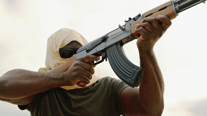 Concept of terrorism. Rebel soldier aiming at targets with an AK-47 machine gun. Portrait. High...