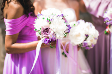 Bride with bridesmaids holding wonderful luxury wedding bouquet of different flowers on the wedding...