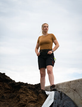 Junge Landwirtin steht an einem gro&szlig;en Maissilagehaufen, landwirtschaftliches Symbolfoto.